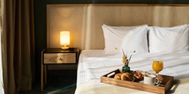 Cozy bed with breakfast tray and lamp on nightstand.