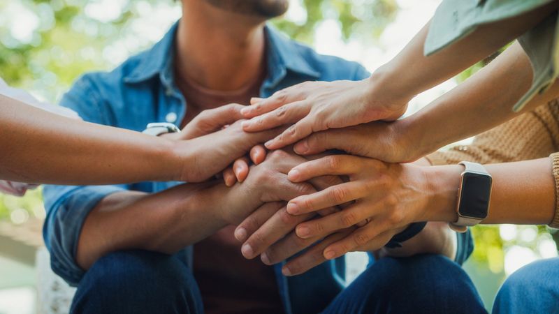 Closeup diverse group of people engaging in supportive group therapy session, sharing personal stories and advice to promote mental health and recovery in park. Mental health community concept.