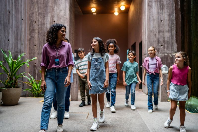 Young teacher walking and talking to students during field trip