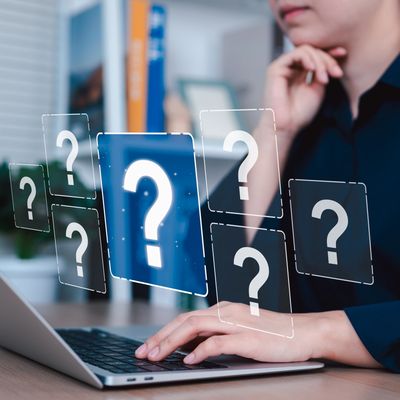 Person using laptop with floating question marks.