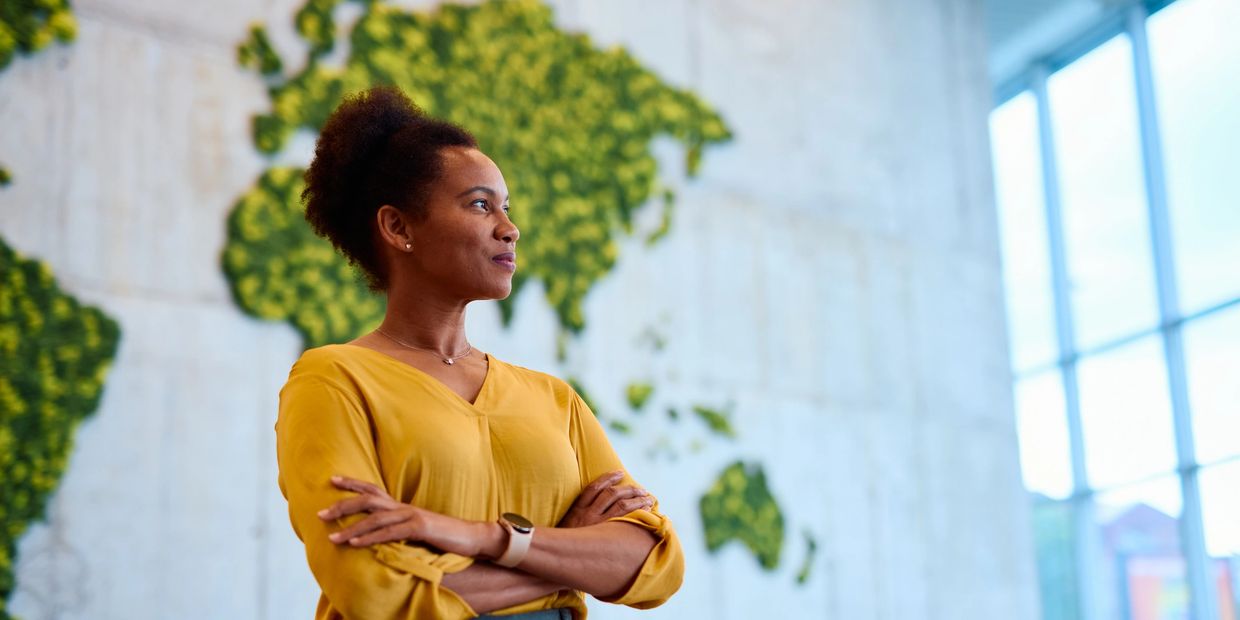 Woman in yellow shirt confidently looking away with map background.