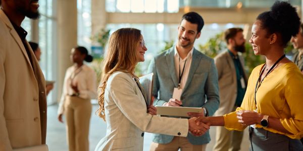 Two professional women shaking hands at a networking event.