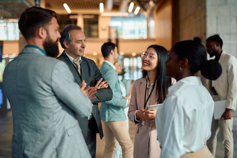 Group of multi-ethnic businesspeople engaging in networking and discussing ideas during a corporate event or convention, fostering collaboration and building professional relationships