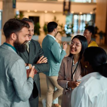 Business professionals network and chat at a corporate event in a modern office lobby.