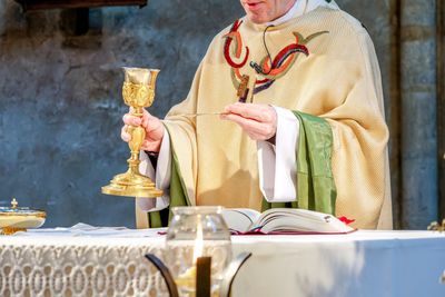 A priest holding a golden chalice during a religious ceremony.
