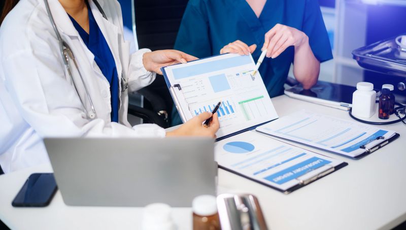 Medical team of doctors and a nurse using laptops in hospital office. Collaboration, diagnosis, and modern technology meet in a healthcare teamwork setting.