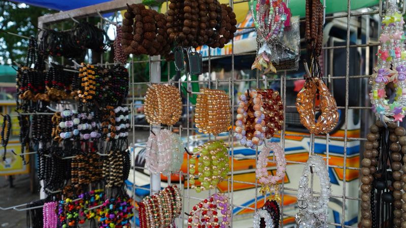 numerous handcrafted jewelry items are showcased at a market stall. different styles of bracelets are arranged neatly. some pieces feature intricate beadwork patterns. the accessories are designed for personal adornment. a retail selling point.