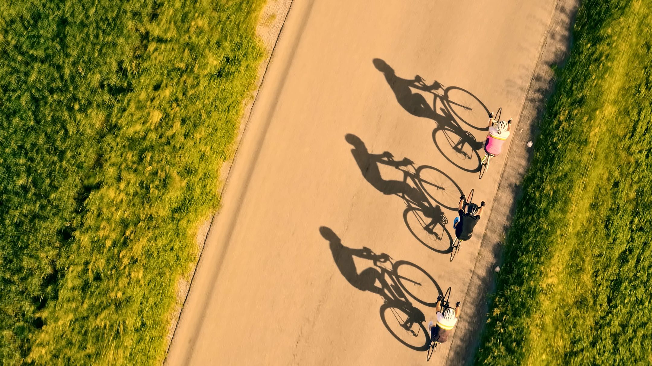 Three cyclists riding on a sunny path.
