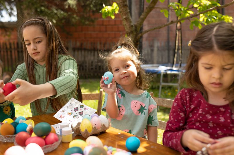 A little girl decorates her Easter egg and proudly shows it to everyone.