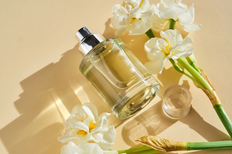Perfume on a beige background in the rays of bright sun with beautiful highlights. High quality photo.