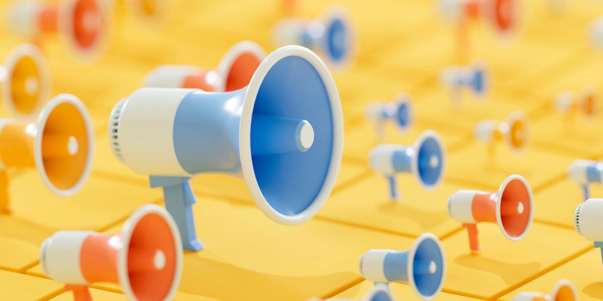 Blue and orange megaphones on a yellow background.