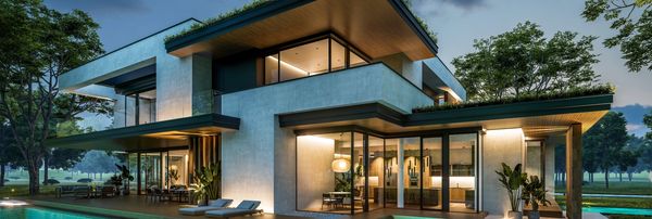 Modern two-story house with large windows and outdoor seating at dusk.