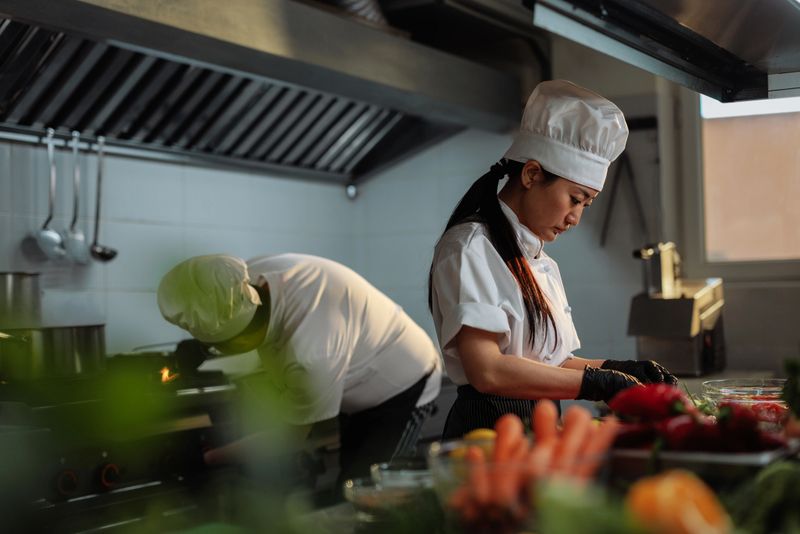 Two chefs collaborating in a bustling restaurant kitchen, skillfully preparing fresh ingredients for a delicious meal