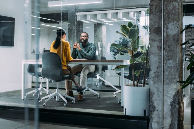 Shot of two colleagues having a discussion in modern office board room.