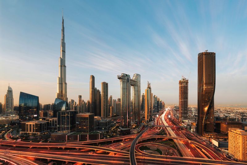 Aerial view of Dubai skyline at sunset. Burj Khalifa and road intersection with traffic lights.