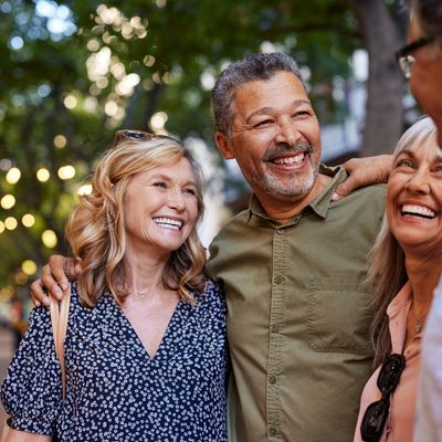 Four friends smiling and enjoying an outdoor evening gathering.