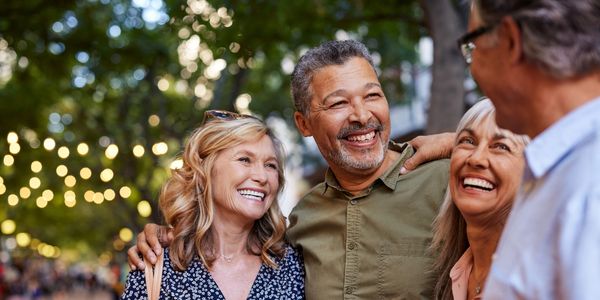 Four friends happily enjoying an outdoor gathering with smiles and laughter.
