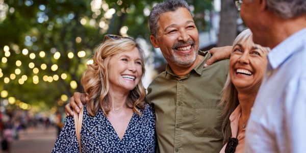 A joyful group of middle-aged friends laughing together outdoors.