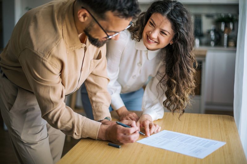 Happy couple reviewing and signing a contract together at home