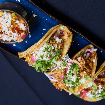 Delicious chicken tacos topped with fresh cilantro and cheese on a blue plate.