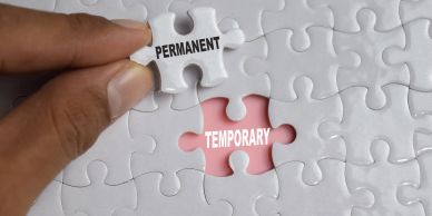 Hand placing a puzzle piece labeled 'PERMANENT' over a 'TEMPORARY' gap.