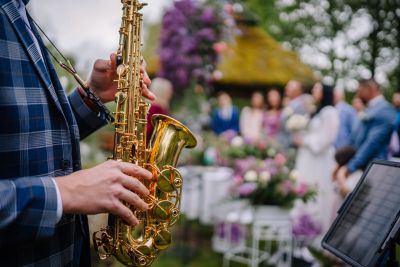 Musician playing saxophone at an outdoor wedding ceremony.