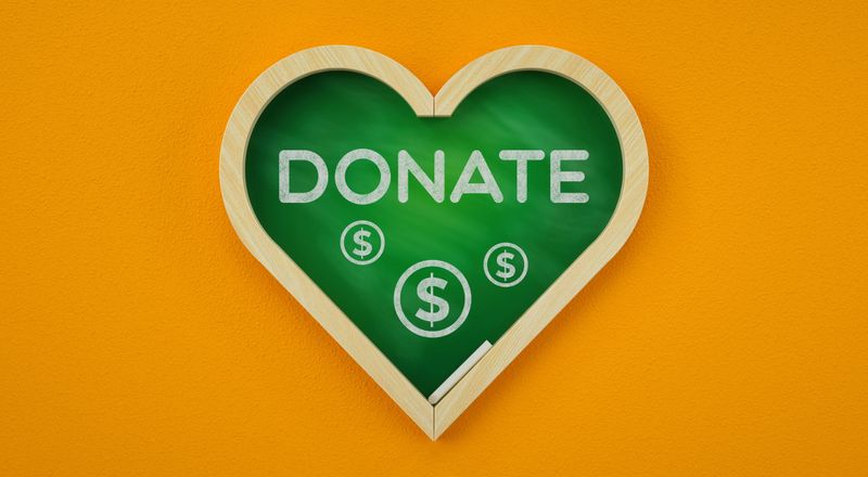 This 3D illustration is a powerful call to action for generosity and support. It features the word "DONATE" and dollar sign symbols written on a heart-shaped chalkboard, symbolizing giving from the heart. Set against a warm orange background, this image evokes feelings of care, compassion, and community. It's an ideal visual for non-profit organizations, fundraising campaigns, charity drives, and social media posts encouraging charitable donations, volunteering, or raising awareness for important social issues.