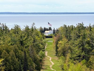 Path through trees to house by water.