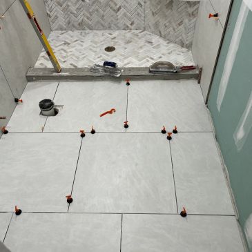 Large tiles being installed on a bathroom floor.