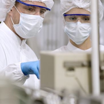 Scientists in lab coats and masks working in a lab.
