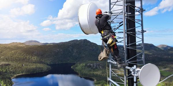 Técnico trabajando en torre de comunicación en la montaña.