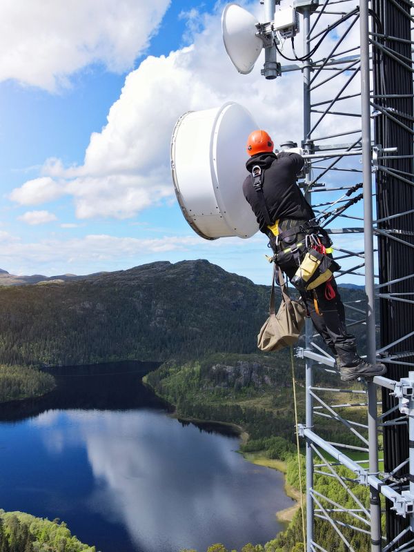 Worker fixing a communication tower on a mountaintop.