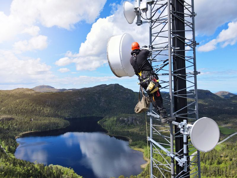 defaultEngineer utility infrastructure worker at big steel mast working with radio link, microwave, 4G, 5G