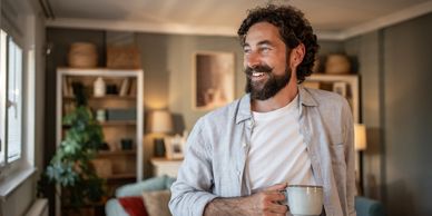 Smiling man with a mug in a cozy living room.