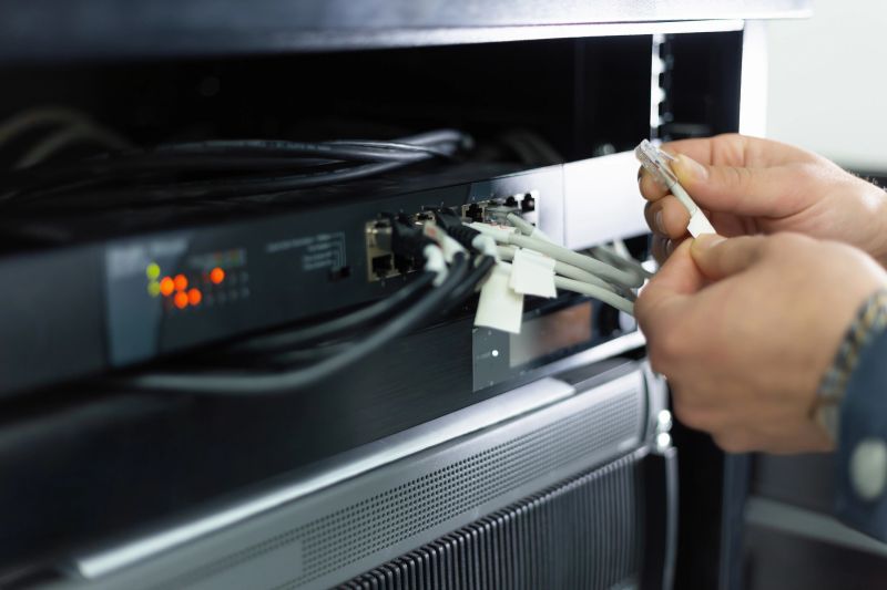 Close-up of a network technician connecting ethernet cable to router in server room