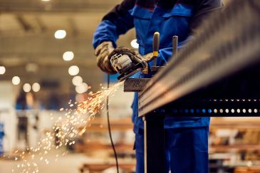 Worker grinding metal with sparks flying.