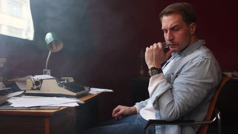 Thoughtful writer in smoky vintage study, cinematic composition with soft-focus on typewriter and smoke.
