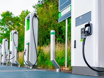A row of electric vehicle charging stations in an outdoor setting.