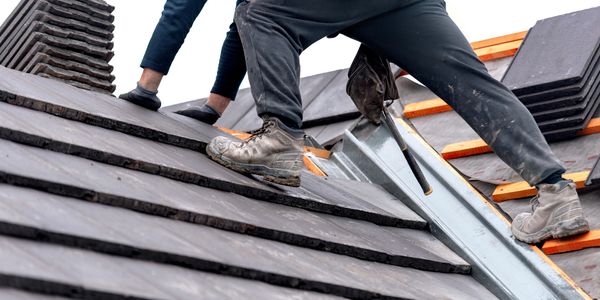 Workers installing roof tiles on a sloped roof.
