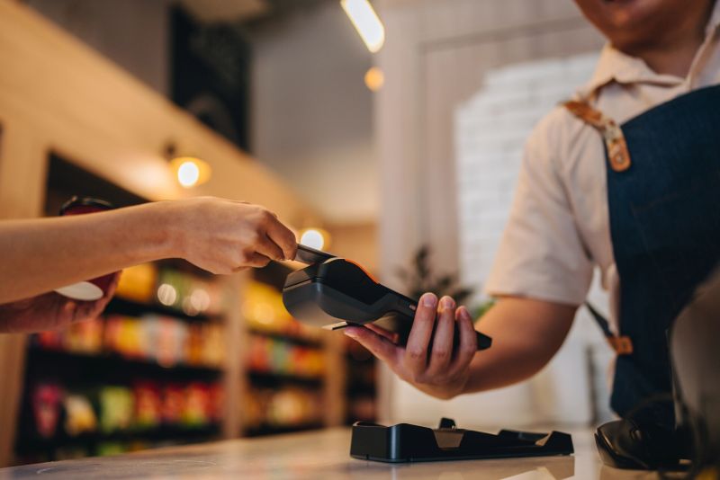 Cafe, waitress and woman with payment on machine for customer service, purchase and digital wallet. Happy, work and fintech pos with phone at restaurant for contactless, banking or mobile transaction