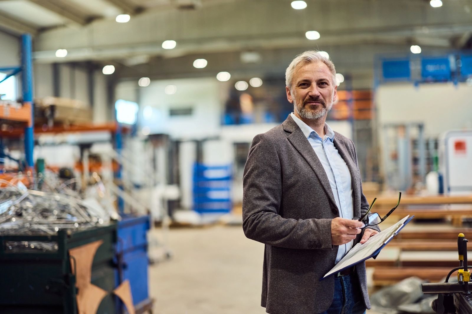 Mature professional manager standing confidently in a large industrial warehouse