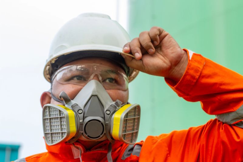Close-up of South east asia man as construction worker wearing a respirator mask and safety glasses. Industrial safety concept