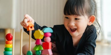 A joyful child playing with colorful wooden blocks and stacking toys.