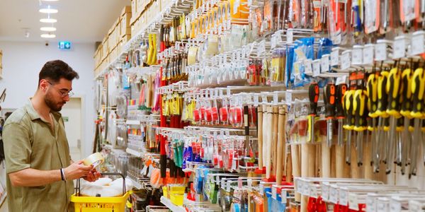 Man shopping for tools in a hardware store aisle.