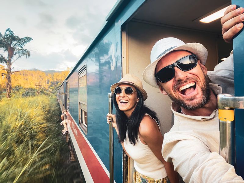 Happy excited passenger travel couple stand by doorstep enjoy popular train ride journey Kandy to Ella and admire Sri lanka lush jungle landscapes. Embrace freedom, curiosity, wonder asia travel