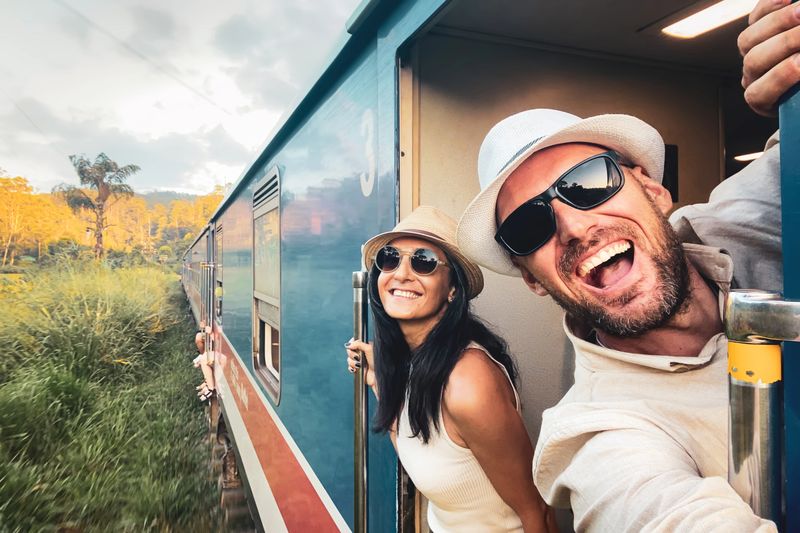 Happy excited passenger travel couple stand by doorstep enjoy popular train ride journey Kandy to Ella and admire Sri lanka lush jungle landscapes. Embrace freedom, curiosity, wonder asia travel