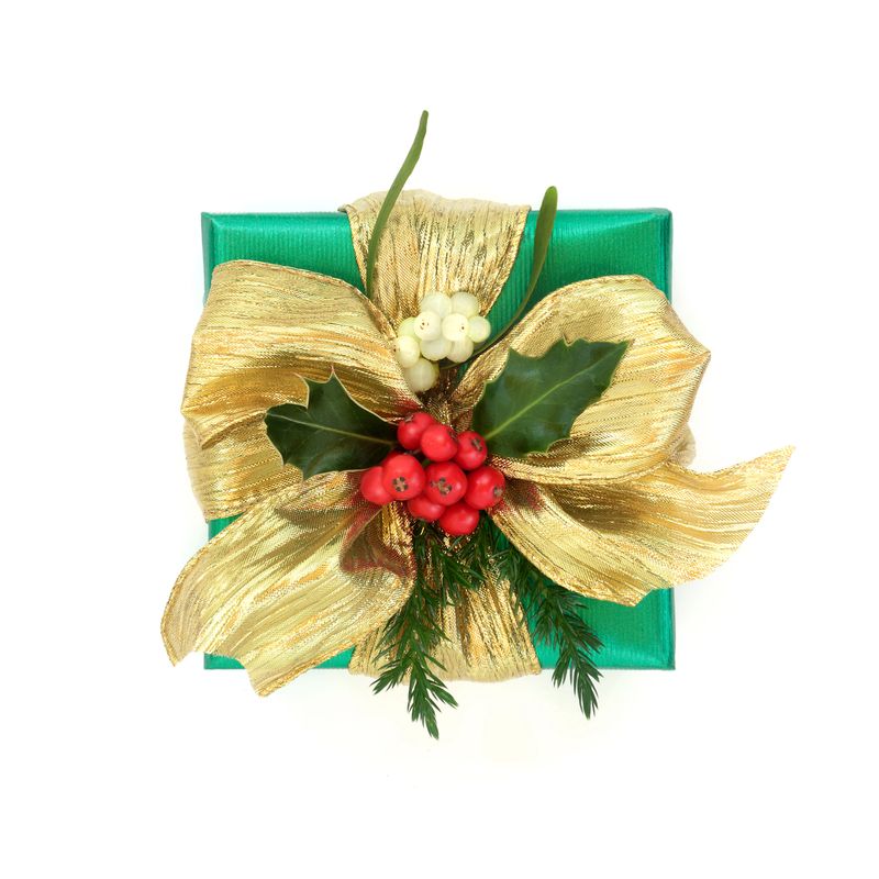 Green gift box, gold bow with holly mistletoe, fir flora decoration on white background. Festive traditional holiday symbol for giving concept.