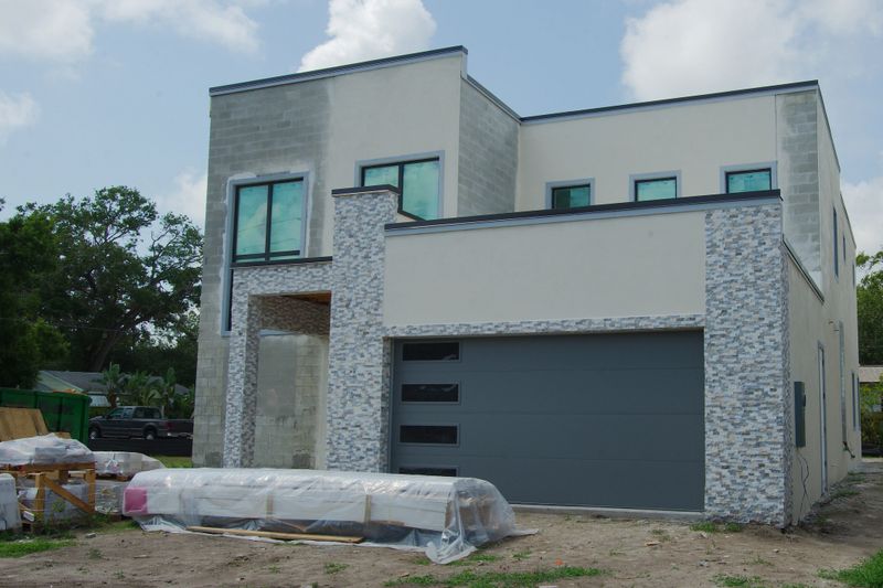 Modern two-story home under construction featuring exposed masonry walls, framed windows, and garage.