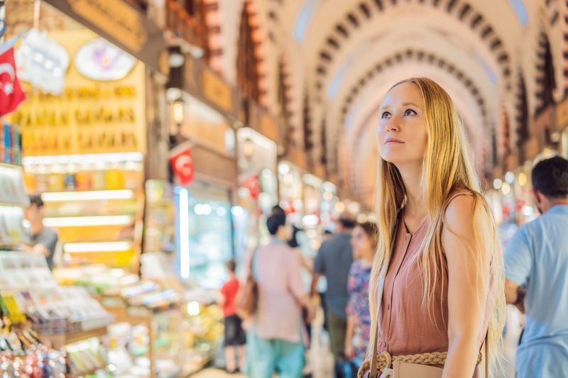 A tourist woman walks among the countless shops at the Grand Bazaar and Egyptian Bazaar in Istanbul. Shopping and travel in Turkey concept. Istanbul historical Egyptian Bazaar. Misir Carsisi, spice market. Turkiye.