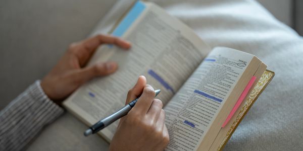 Person studying and highlighting text in an open book.